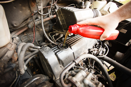 Car servicing mechanic pouring oil to engine. Closeup of fresh oil being poured into a car.